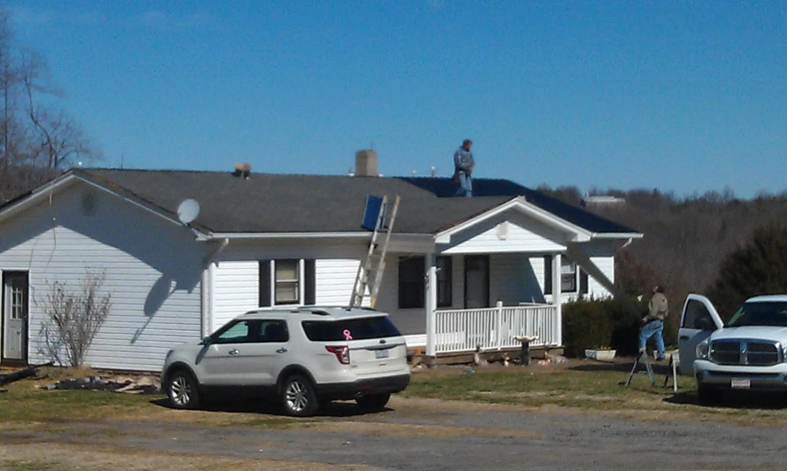Roofers stripping shingles from a white ranch house roof in Temple